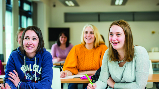 Classroom with students smiling and writing on notepads
