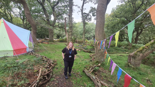 woman standing in forest with bunting hanging from trees and a colourful tipi