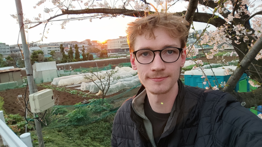 Elis taking a picture of himself in front of a cherry blossom tree