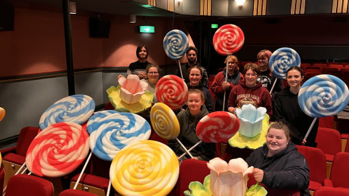 BA Set Design students sitting down in the Lyric theatre holding the giant lollies that they've created for the production