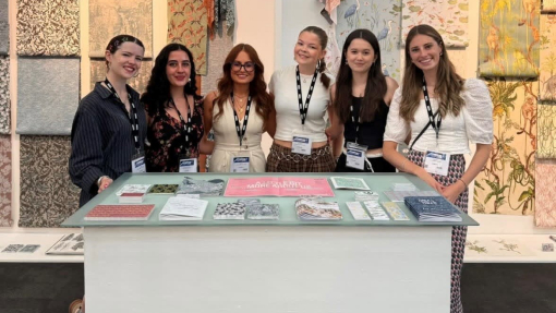 Six smiling, happy and proud students pictured against a colourful backdrop of their creative work.