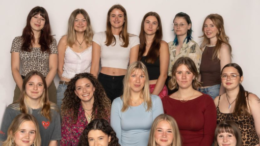 A group of happy, smiling students sat and standing against a white background.