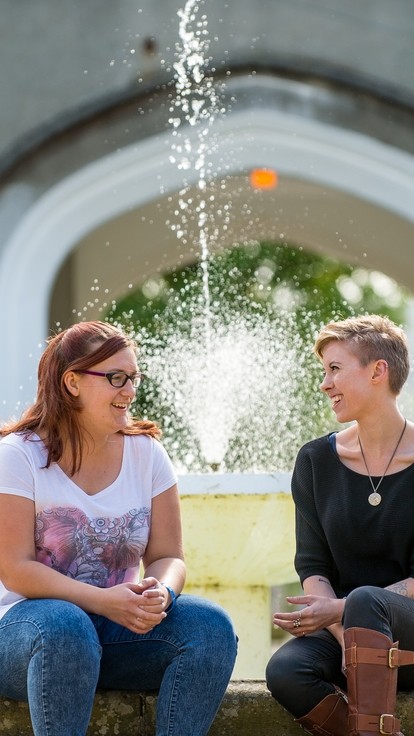 Two students siting in front of the Lampeter campus fountain