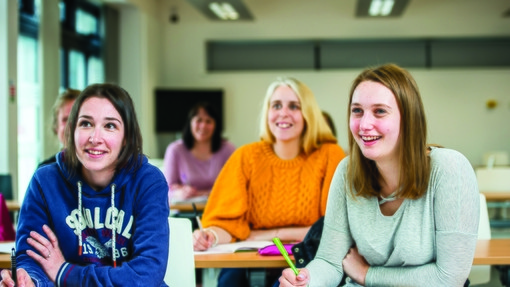 Classroom with students smiling and writing on notepads