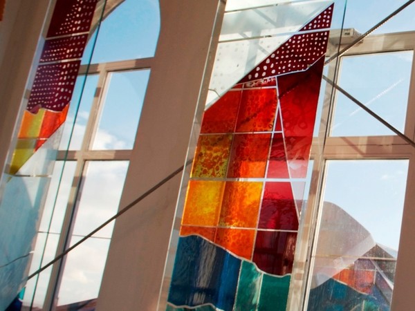 Stain glass panels in front of windows catch the light.