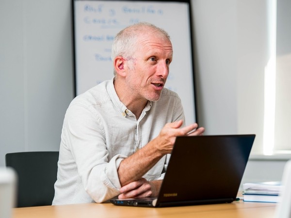 Staff member in discussion with laptop in front of him