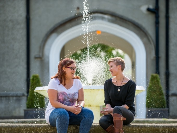 Two students siting in front of the Lampeter campus fountain