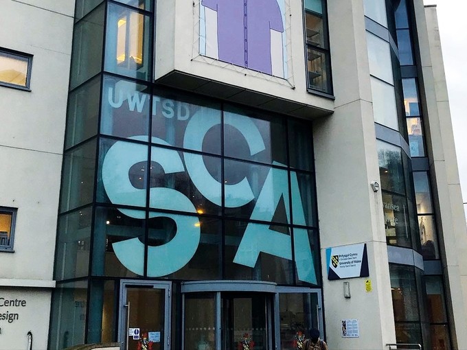 The large modern window over the entrance to the Dynevor displaying the jaunty six-foot-high letters SCA.