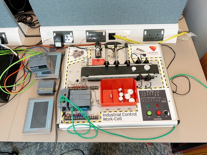 An industrial control work-cell: a complex board including control switches, pneumatic cylinders, and LED lights.