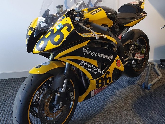 A motorbike on display with UWTSD branding and colours.
