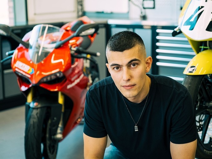 Vinicius Dreher sitting in a motorbike workshop.