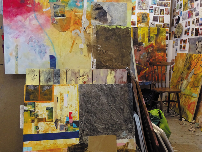 A room full of painted boards as well as square sketches and cuttings stuck to the walls.