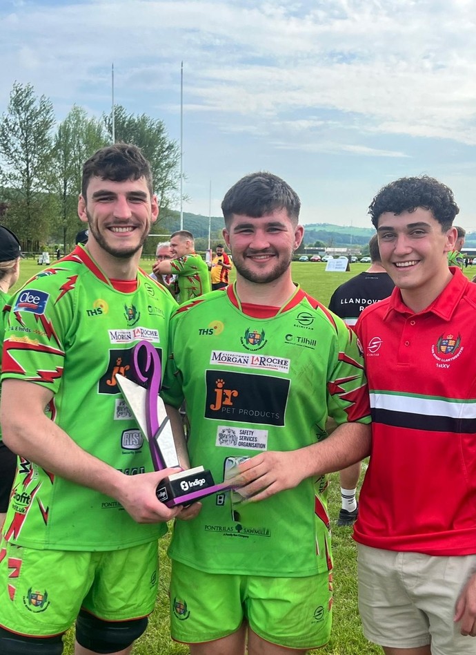 3 students from The Academy of Sport wearing Llandovery RFC kit holding the trophy
