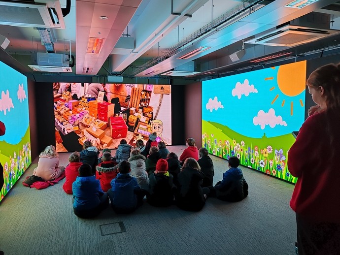 A group of school children sitting in the immersive room 