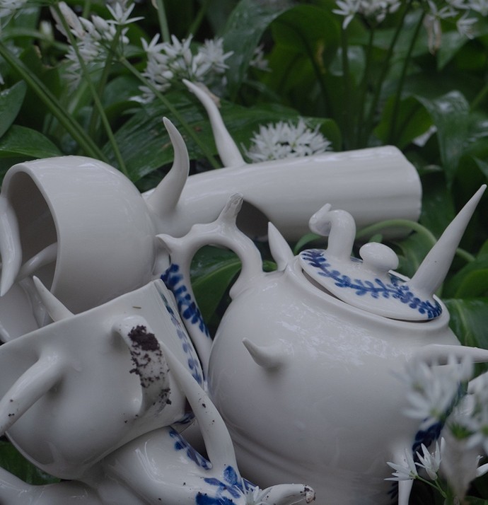 White crockery with tentacle-like handles and spouts lies in a small heap in a bed of wild garlic.