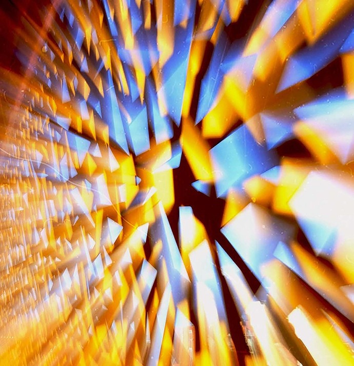 A kaleidoscopic digital pattern of blue and radiant yellow shards. 