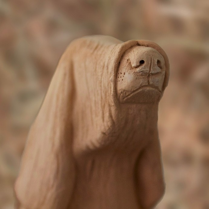 A simple pottery figure resembling the snout, head, and ears of a long-haired dog.