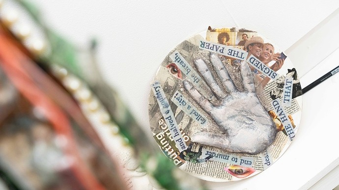 Plaster cast of a hand in the middle of the paper disc with scraps of text reading: The hand that signed the paper – and halved a country – felled a city.