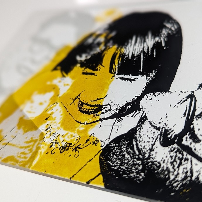 A complex design on glass showing the smiling faces of a man and a woman inked in black with an additional layer of yellow; gaps in the yellow outline two children.