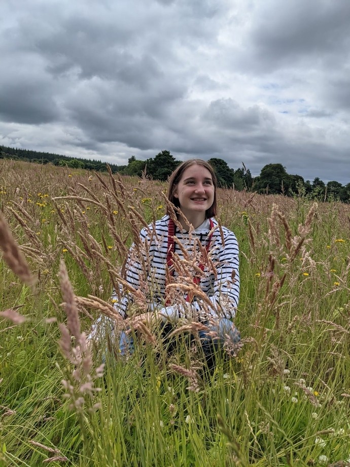 An image of Aimee sitting in a field