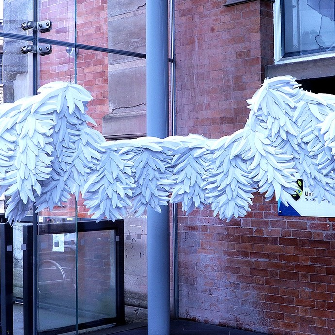 A long structure composed of artificial white feathers hanging in the lobby of the Alex; in size and form it resembles a Chinese Dragon puppet. 
