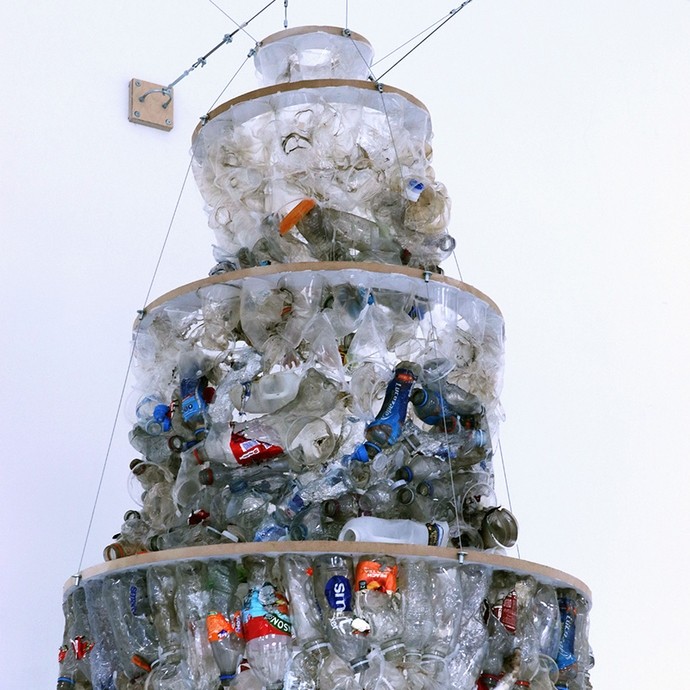 A three-layered cylindrical pyramid composed of empty plastic bottles and suspended from the ceiling. 