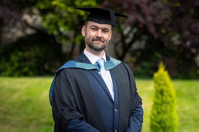 Headshot of Benedict Gibson in his graduation gown on Carmarthen campus
