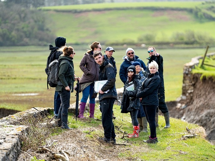 A study group stand on top of Cwm Ivy sea wall, close to a large rupture in the earth bank. 