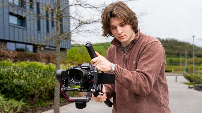 A young man films with a Lumix camera on a gimbal. 