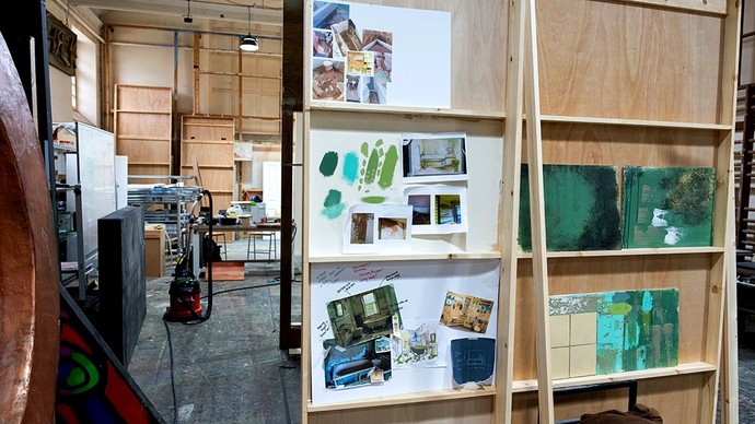 A workshop with rough timber shelving supporting a collage of different set designs and notes.