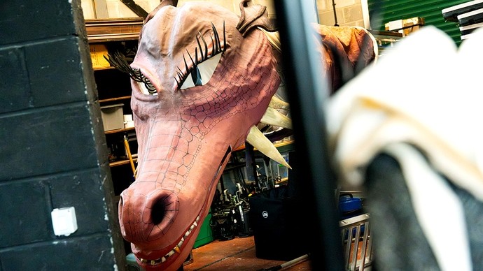 A giant red papier-mâché dragon head in a workshop ready for deployment.