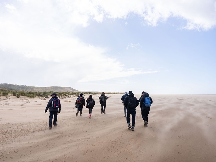 Environmental study group walking across the broad, flat expanse of Whiteford Sands. 