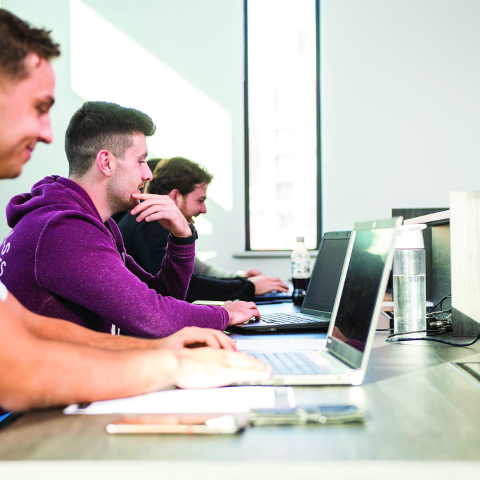 Row of students working on laptops