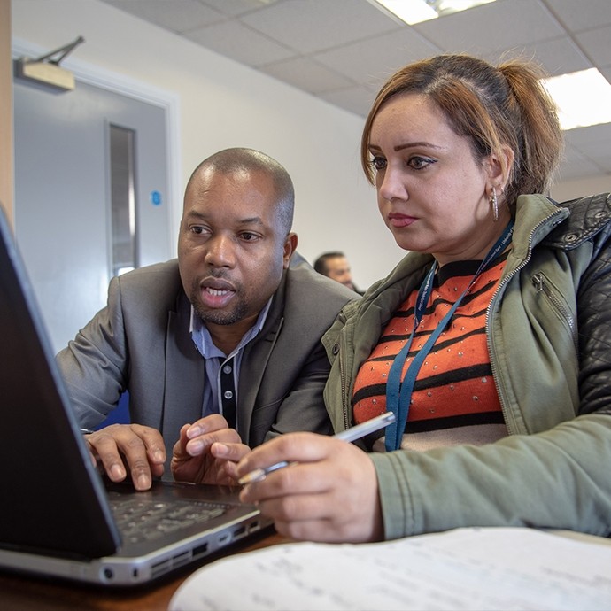 Staff member and student looking at a laptop