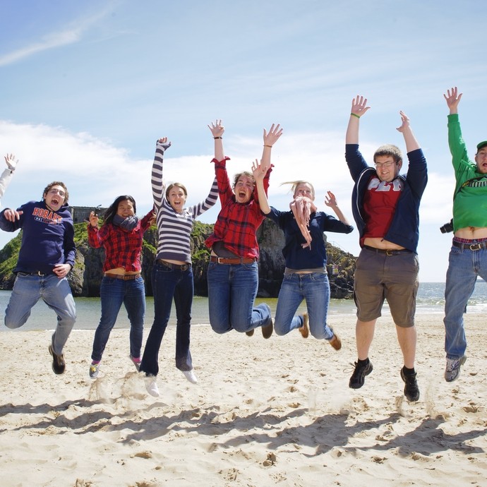 Group of students jumping on the beach