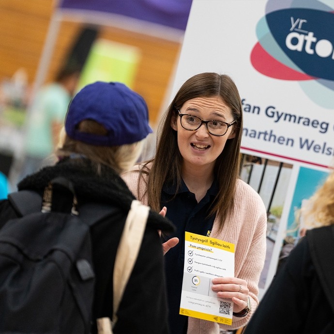 Welsh language staff member chatting at a recruitment fair