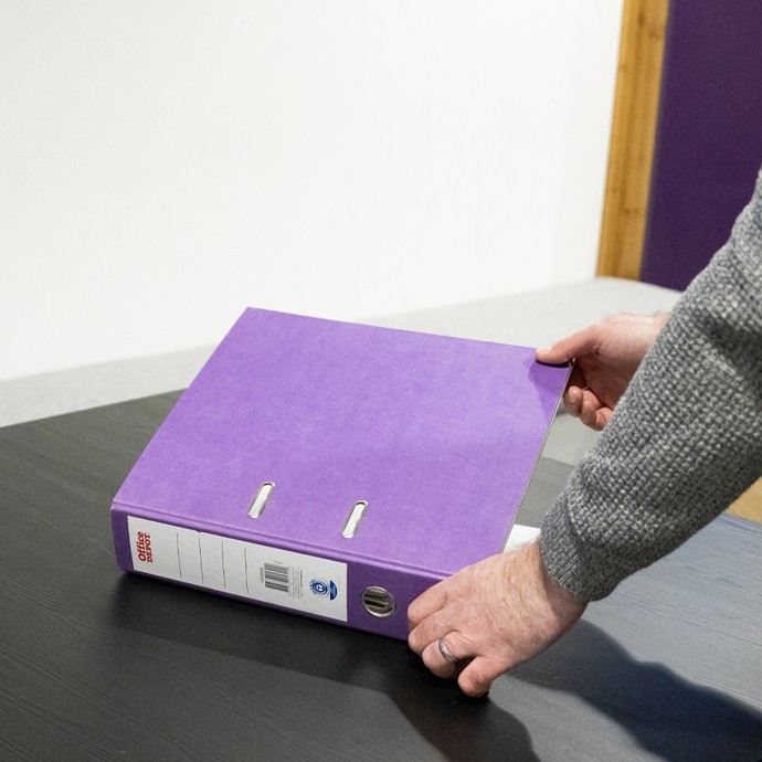 Person opening a purple ring binder 