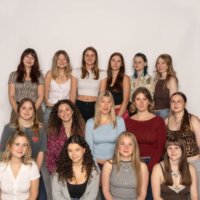 A group of happy, smiling students sat and standing against a white background.